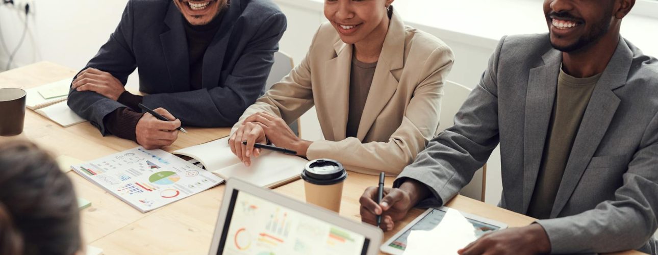 Colleagues in a meeting reviewing charts on a laptop, printed report, and tablet in a bright office, used as the featured image for small business SEO in Asheville.